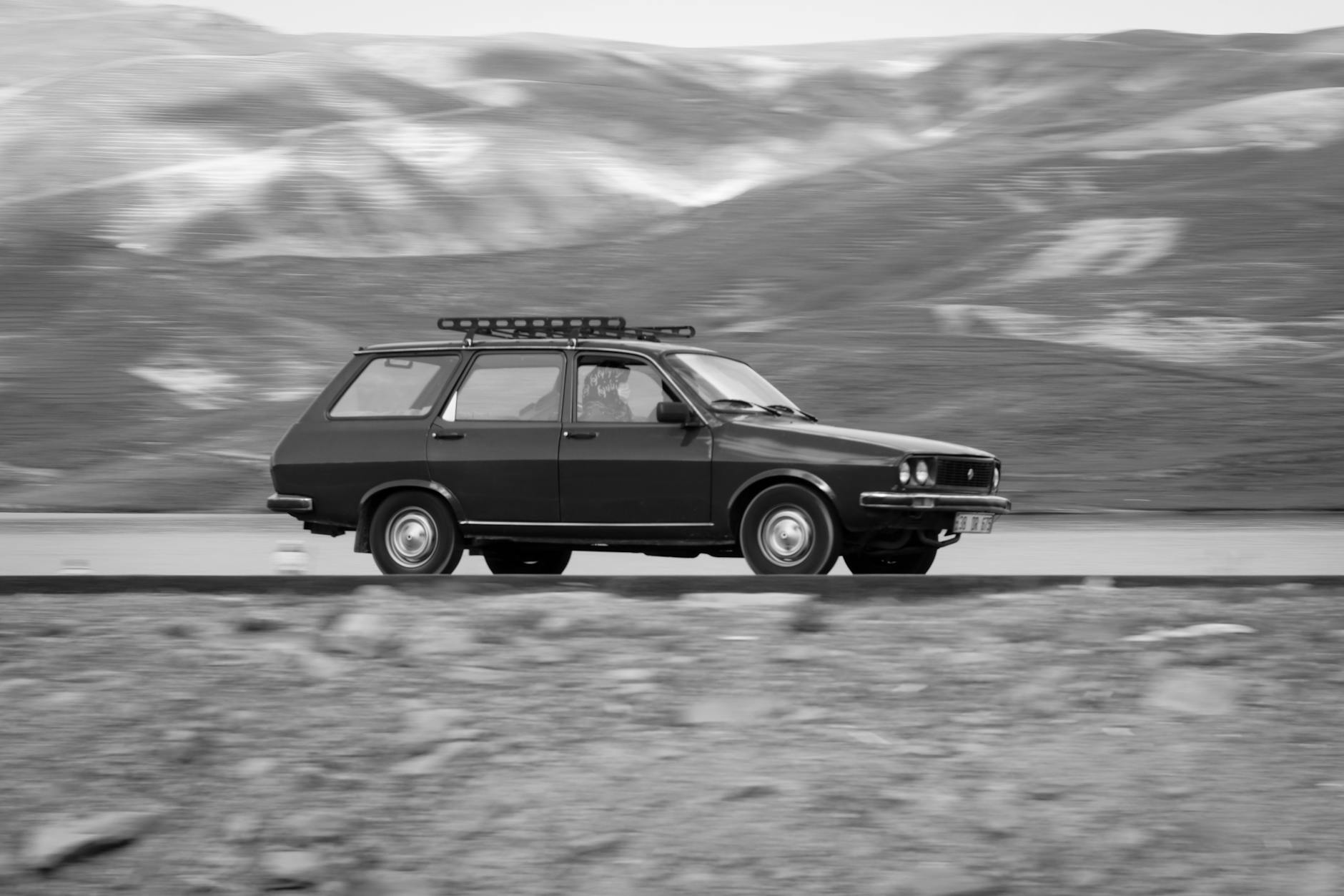 Kombi jadące górską drogą w czarno-białej tonacji